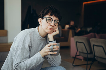 Sleepy young woman with a cup of coffee in the morning in the office.