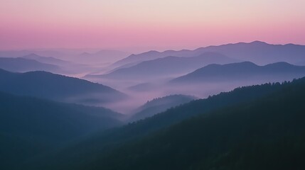 Fototapeta premium At sunrise, pink and purple hues fill the misty mountains
