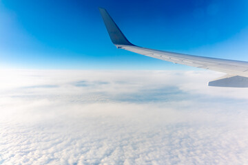 View from the airplane window at a beautiful cloudy sky and the airplane wing
