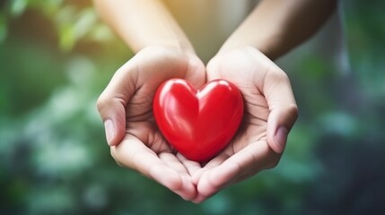 Tender hands gently hold a vibrant red heart against a soft green background, symbolizing love and health.