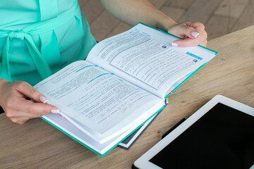 Fototapeta premium A person studies a textbook alongside a digital tablet, symbolizing modern education and learning challenges, emphasizing lifelong education