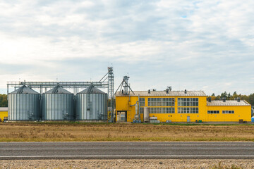 silver silos on agro manufacturing plant for processing drying cleaning and storage of agricultural products, flour, cereals and grain. Large iron barrels of grain. Granary elevator