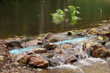 small waterfall flow over the river in Thailand with blue pipeline