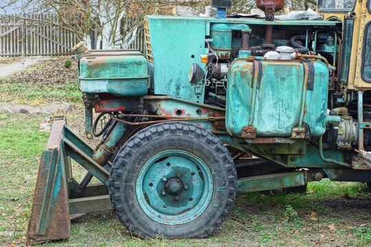 One Small Black Rubber Tire With Pattern Old With Iron Green Disk Flat Industrial Round Wheel With Side Of Heavy Tractor Stands On The Ground In The Daytime On The Street