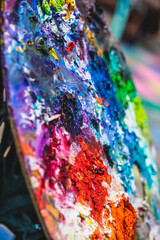 Closeup of messy, colorful artist's paint palette with a lot of paint on it