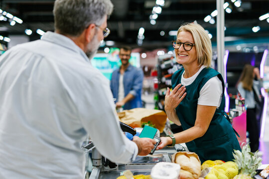 Customer paying with smartphone at grocery store checkout counter