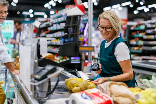 Senior cashier scanning groceries at supermarket checkout counter