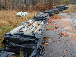 Eternit sheets dismantled from the roof, placed on pallets and wrapped in black foil.