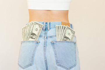 A shoot of a young Caucasian woman with a fan of dollar bills sticking out of the back pockets of...