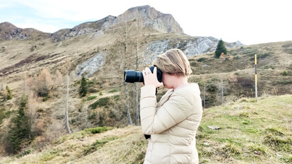 A Caucasian woman enjoys outdoor photography in a scenic mountain landscape, capturing nature's beauty, ideal for content on travel and leisure Dolomite Alps, Dolomites