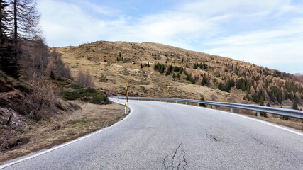 Mountain road in the autumn landscape with bare trees, illustrating the concept of solitude and adventure travel Dolomite Alps, Dolomites