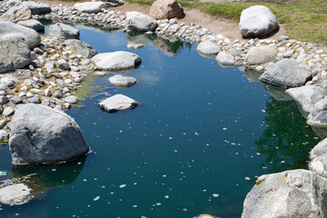 dark blue water with rocks greenery and rocks