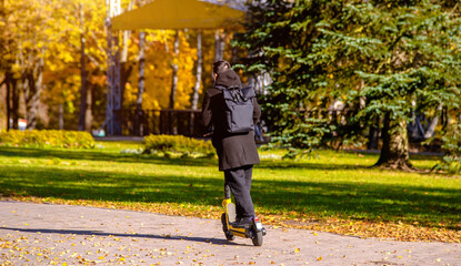 Fototapeta premium A guy rides an electric scooter in the autumn Park