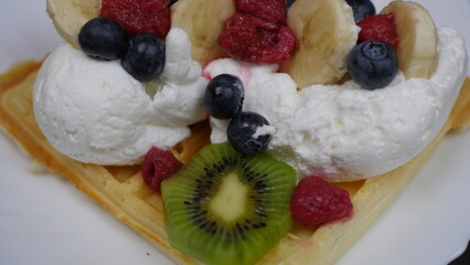 Waffles with whipped cream, blueberries, bananas, raspberries, and kiwi