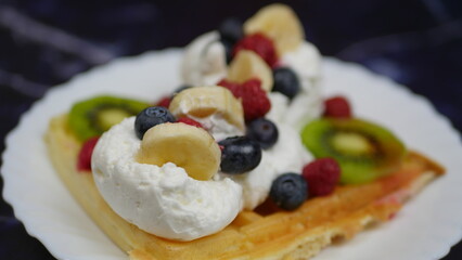 Waffles with whipped cream, blueberries, bananas, raspberries, and kiwi