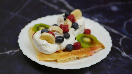 Waffles with whipped cream, blueberries, bananas, raspberries, and kiwi