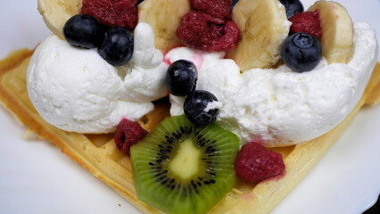 Waffles with whipped cream, blueberries, bananas, raspberries, and kiwi
