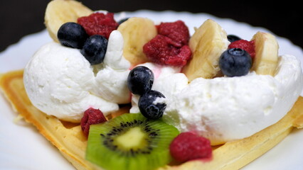 Waffles with whipped cream, blueberries, bananas, raspberries, and kiwi