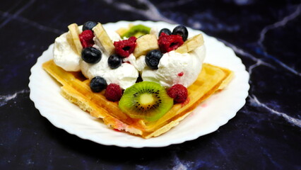 Waffles with whipped cream, blueberries, bananas, raspberries, and kiwi
