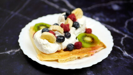 Waffles with whipped cream, blueberries, bananas, raspberries, and kiwi