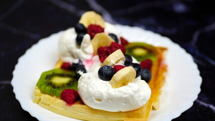 Waffles with whipped cream, blueberries, bananas, raspberries, and kiwi