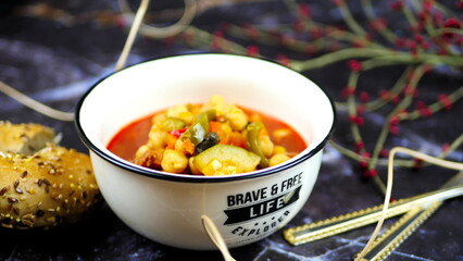Dish with chickpeas, peppers, carrots and other vegetables with a whole grain roll and a glass of wine

