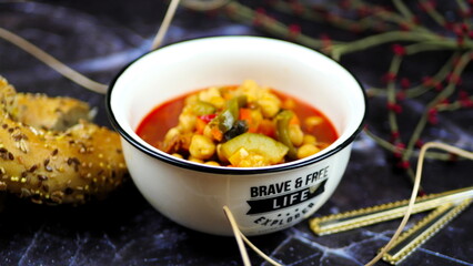 Dish with chickpeas, peppers, carrots and other vegetables with a whole grain roll and a glass of wine
