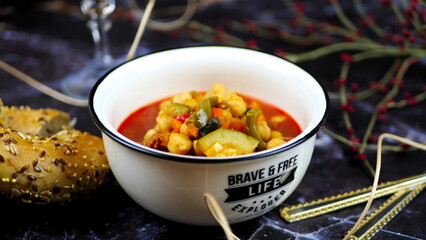 Dish with chickpeas, peppers, carrots and other vegetables with a whole grain roll and a glass of wine
