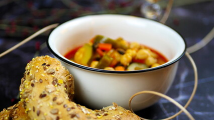 Dish with chickpeas, peppers, carrots and other vegetables with a whole grain roll and a glass of wine
