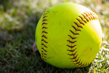 girls yellow softball sitting on grass
