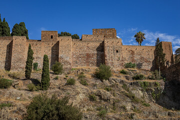 Scenic view of ancient ruins of Malaga Roman Theater (El Teatro Romano, I century BC) with historic Roman semi-circular seating at foot of famous Alcazaba fortress. Malaga, Andalusia, Spain.