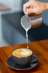 closeup hand doing hot latte art coffee
