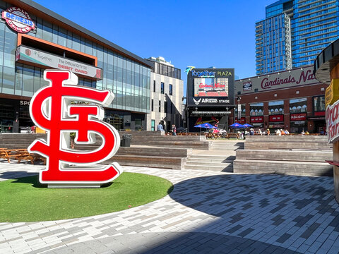 St. Louis, MO - USA: The large red and white St. Louis Cardinals logo in Ballpark Village near Busch Stadium with bright sunshine and shadows. Ballpark Village in the distance.