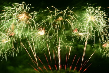 Colorful fireworks celebration with people and the city night light background at the seaside. International firework festival at Pattaya, Thailand.