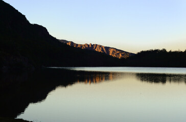 Landscape of Natacion Lake with mountain reflection during sunset as part of a challenging mountain huts circuit for backpacking, camping, and trekking in El Bolson town, Rio Negro, Argentina