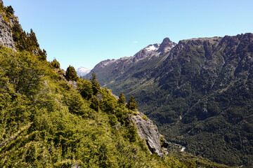 Beautiful close up of snowy rocky mountains and forest with green trees part of a challenging trekking trail that connects Natacion Lake and Cajon del Azul landmarks in El Bolson, Rio Negro, Argentina