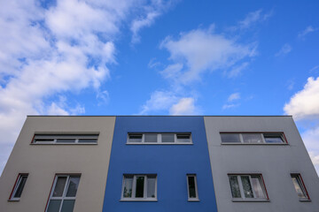 Apartment block with blue centre stripe and blue sky with clouds