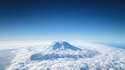 A photo of an isolated snow covered volcano taken from the air, with a clear blue sky and white clouds below it