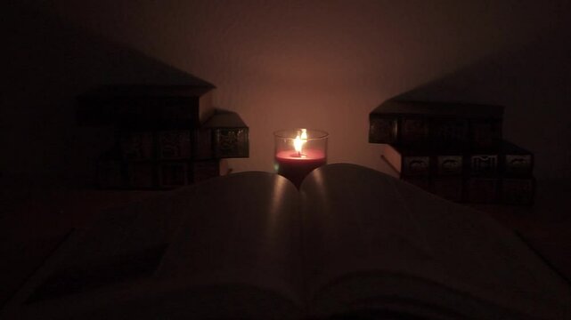 Libro abierto con vela para iluminar en la noche para estudiar