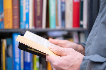 book in male hands, street urban library shelf, reading book, reading and education in urban environment, urban culture and public spaces, people can enjoy reading outdoors, selective focus