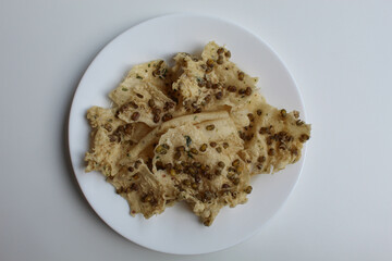 Traditional crackers with mung bean sprinkles from Indonesia, called Rempeyek Kacang Hijau. On white plate. Isolated on white background, flat lay or top view