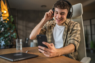 Young smile man listen music on headphones and mobile phone at home