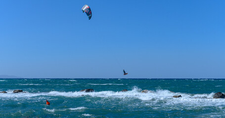 Kite surfer soaring above waves on a bright sunny day at the coast