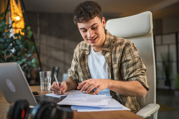 Focused young adult man write notes in notebook prepare for exam