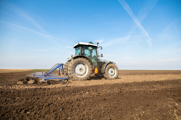 Powerful tractor cultivating fertile soil under clear skies, ready for sowing
