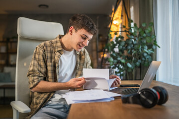 Focused young adult man write notes in notebook prepare for exam