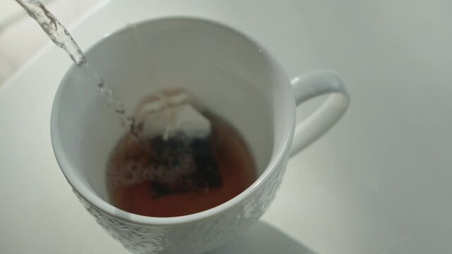 Pouring hot water in cup with tea bags 