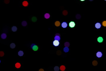 Una toma de cerca de una fondo abstracto de luces de navidad de diferentes colores en la oscuridad. Desenfoque bokeh