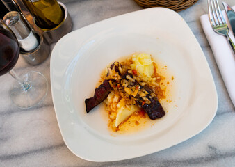 Dish of day from chef of elite restaurant is beef jerky with Creole sauce, garnished with mashed potatoes. Small portion of food is served for dinner at catering establishment.