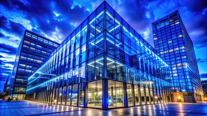 Fototapeta premium Stunning Panoramic View of Blue Mirrored Glass Facade Illuminated by Blue Lamps from a Low Perspective at Night, Modern Architecture, Urban Scene, Vibrant Colors, Contemporary Design